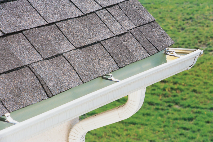 white gutters of a white house with an asphalt roofing